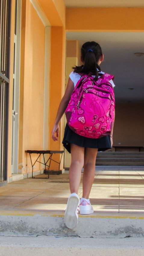 Kind mit Schulranzen auf dem Weg zur Schule